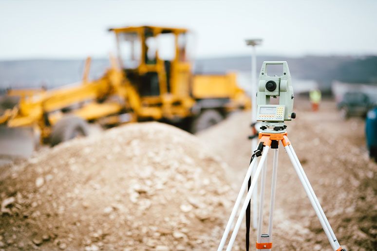 Eine Baustelle mit einem Vermessungsgerät und einem Kraftfahrzeug